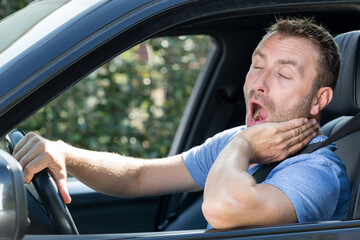 man yawning in car during traffic jam