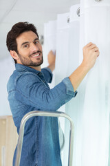 young man installing curtains over window