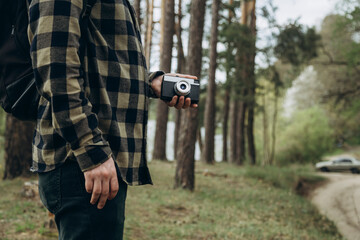 Male photographer with a film camera in a pine forest, analog photography.