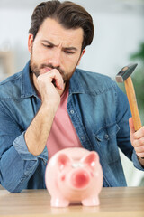 helpless man with piggy bank and hammer