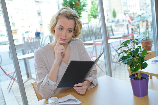 beautiful woman ordering from menu in restaurant