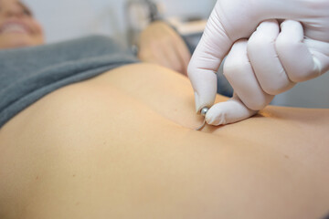 woman getting a belly piercing done - obrazy, fototapety, plakaty