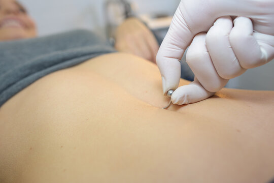 woman getting a belly piercing done