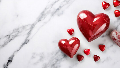 Minimalist setup of two large red glossy marble heart shapes accompanied by smaller hearts on a white marble background.