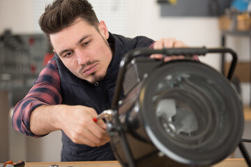 young handsome professional plumber worker installing heating radiator