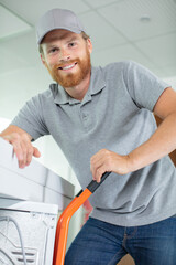 young male professional man moving a washing machine