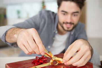 man tying a bow on a christmas gift