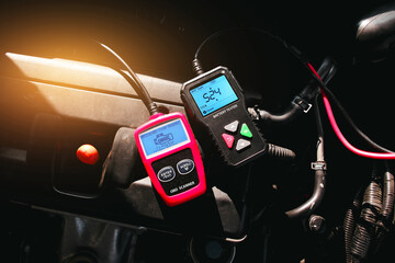 Battery tester and OBD or OBD2 scanner on engine compartment , Car maintenance service concept - obrazy, fototapety, plakaty