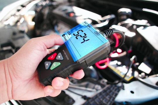 Car technician checking CCA Cold Cranking Amp of car battery with battery tester in the auto repair garage , Car maintenance service concept