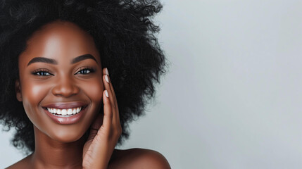 beautiful black woman with radiant skin smiling while touching her face on a white background,...