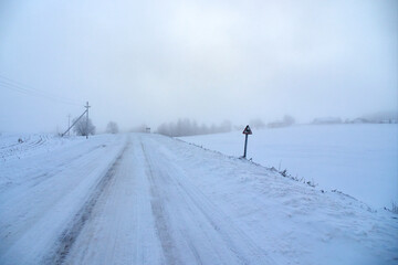 Rural winter landscape at dawn. Country road covered with snow