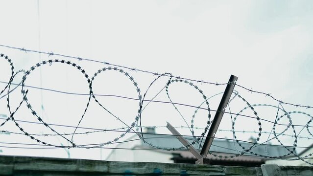 Overview of the electric chain-link fence with barbed wire of the prison on a rainy day. Drops of rain on the fence. High quality FullHD footage