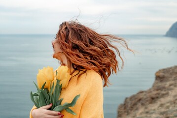 Portrait of a happy woman with hair flying in the wind against the backdrop of mountains and sea....