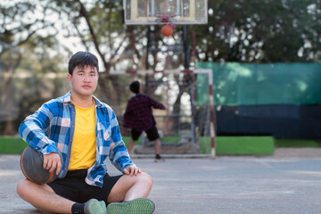 Asian boys in plaid shirt holding and waiting for basketball playing with friends at outdoor...