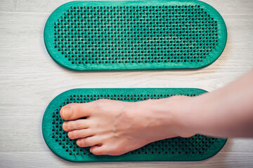 Close-up of Sadhu board with human foot. Feet standing on nails bed. Yoga exercise and spiritual meditation practice desk. Alternative medicine and treatment