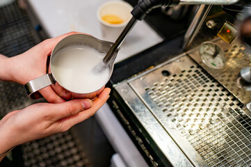 Barista skillfully steaming milk for a fresh cup of coffee, capturing the intricate details of...