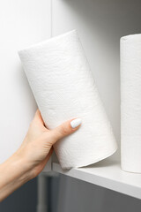 housewife takes out a roll of paper towel from the kitchen cabinet.