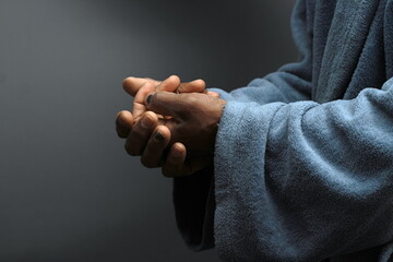 praying to god with hands together Caribbean man praying on black background with people stock...