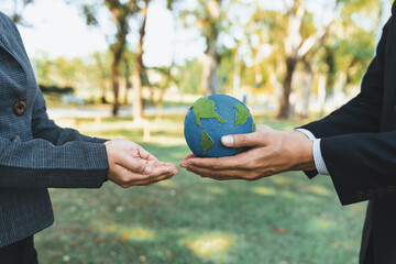 Earth day concept, businessman giving Earth globe to colleague as CSR corporate social responsible principle to promote environmental awareness and embrace ESG for greener and sustainable future. Gyre - obrazy, fototapety, plakaty