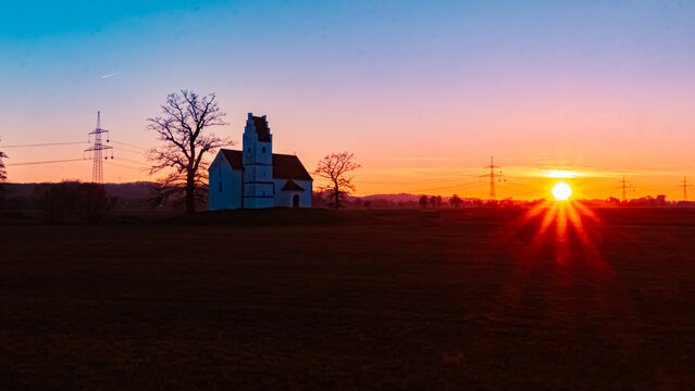 Sunset with a church silhouette and a sunstar at Huett, Eichendorf, Dingolfing-Landau, Bavaria, Germany