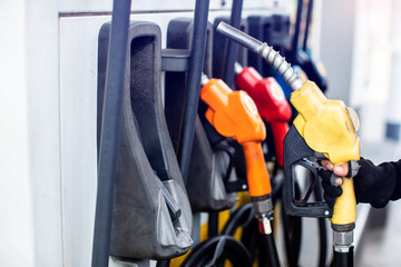 A gas station attendant holds a fuel nozzle at a gas dispenser in a gas station.