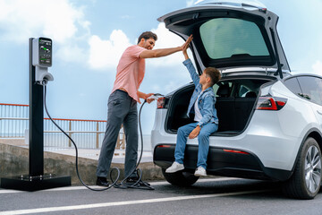 Family road trip vacation traveling by the sea with electric car, father and son high five after...