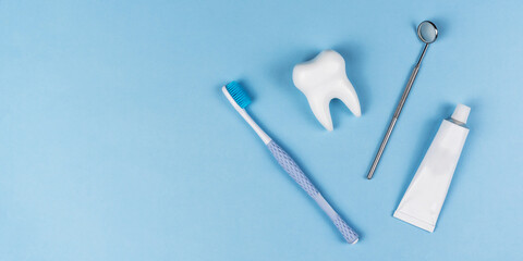 Healthy white tooth, toothpaste and toothbrush on a blue background. The concept of dentistry, health, health care, oral care. Oral hygiene, professional teeth cleaning. Banner for a dental clinic