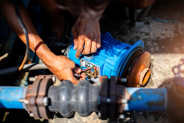 Selective focus to hand of plumber repair and remove motor of centrifugal water pump. Plumbers...