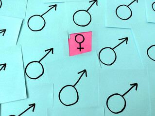 Women's inequality concept shown as sticky notes in pink and blue. The glass ceiling is a social...