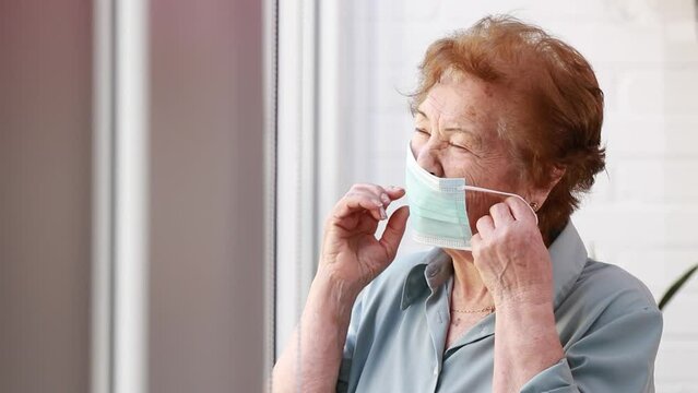 senior woman putting on face mask at home