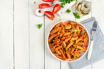 Classic italian pasta penne arrabbiata with vegetables on white wooden table. Penne pasta with sauce arrabbiata. Top view, overhead