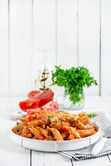 Classic italian pasta penne arrabbiata with vegetables on white wooden table. Penne pasta with sauce arrabbiata.