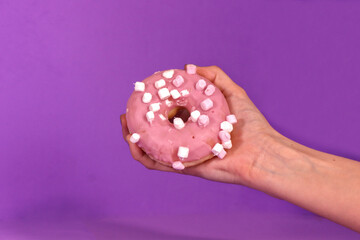 Woman hand holding pink donuts on magenta background