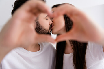 Photo of flirty charming husband wife nightwear cuddling kissing showing heart indoors house bedroom - obrazy, fototapety, plakaty
