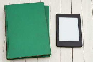 Retro old green book on a desk with an ereader