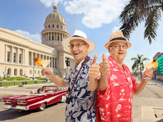 Elderly male tourist with cocktails gesturing thumbs up in Havana