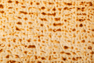 Close up view of matzah, an unleavened flatbread significant in Jewish Passover. The surface is...