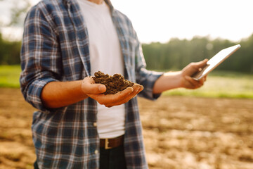 The male hands of an agronomist sort through and check the quality of the soil. Smart farm. ...