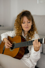 portrait of a beautiful curly woman playing the guitar
