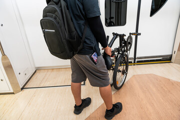 Rear view of a man carrying his Foldable bicycle inside the metro