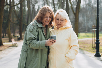 Women use smartphone to find what they are interested in outdoors. Searching information data on internet, networking concept. Friends watching videos on a smartphone in park