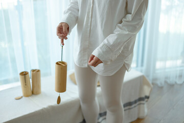 a woman in a white outfit listens to the sound of bells of the elements