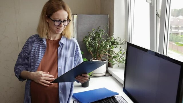 Pregnant woman at work in the office, organizing documents, balancing work and pregnancy