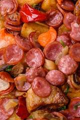 Grilled potatoes cut into slices with hunting sausages with garlic, onion