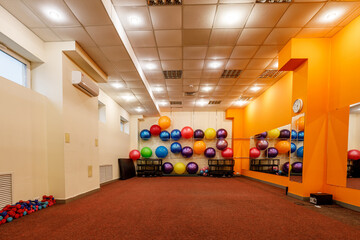 Empty spacious fitness room with fitballs against the wall and dumbbells on the floor