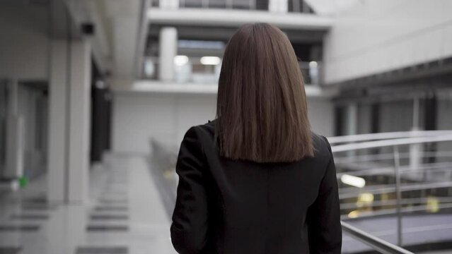 Rear view shot of business lady introducing new modern office. Discover new workspace. Open space office. Rear view follow shot of walking successful business woman. Excursion from central office