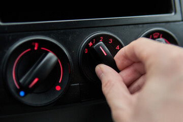 Man hand turns the climate heater control wheel in a car. Temperature and blow air conditioner...