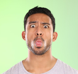 Obraz premium Man, portrait and humor in studio, tongue and goofy comic or funny face on green background. Male person, mockup space and guy for joke or comedy, student and awkward for crazy character and quirky