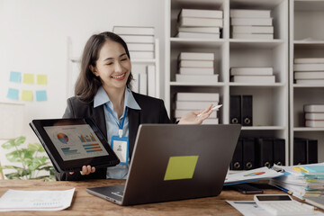 Asian businesswoman working in office with documents and laptop The worker documents, calculates financial indicators, smiles and is happy about the success of the business.