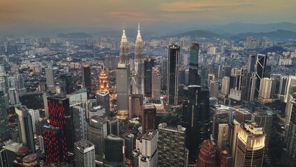 Aerial evening shot of Kuala Lumpur city center at sunset, Malaysia. Flying over illuminated...